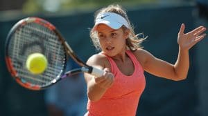14 year old girl who is focused playing tennis