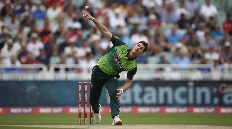 A professional cricketer bowling a delivery with focus