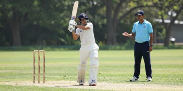 Young cricketer batting with coach